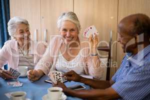 Happy senior people playing cards while having coffee