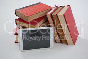 Books and digital tablet arranged on white background