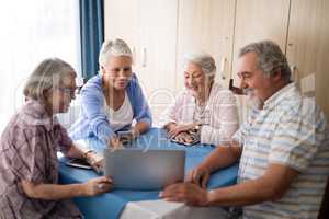 Smiling senior man showing laptop to women at table