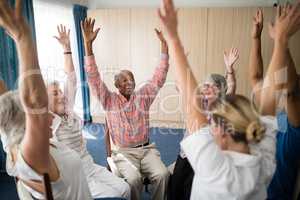 Cheerful seniors and female doctor sitting with raised hands
