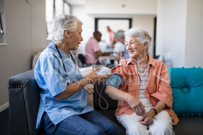 Nurse checking senior woman blood pressure at nursing home