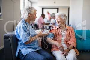 Nurse checking senior woman blood pressure at nursing home