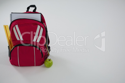 Schoolbag with various supplies and apple