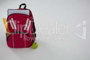 Schoolbag with various supplies and apple