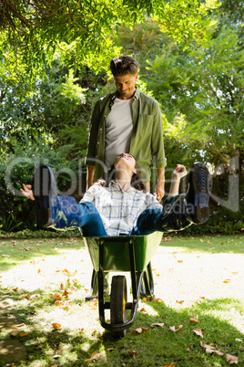 Man interacting with woman while pushing wheelbarrow in garden