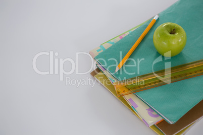 Apple, scale and pencil on book stack