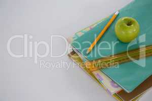 Apple, scale and pencil on book stack