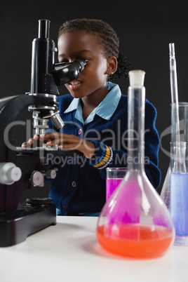 Schoolgirl using microscope against black background