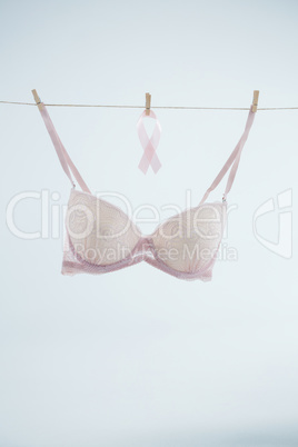 Pink Breast Cancer ribbon hanging by bra on string