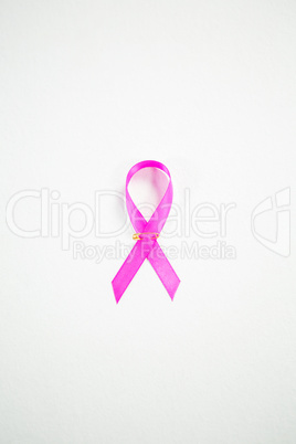 Directly above view of pink Breast Cancer Awareness ribbon with safety pin