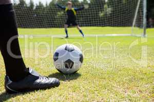 Low section of soccer player with ball against goalkeeper