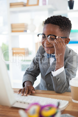 Happy businessman wearing eyeglasses while using computer