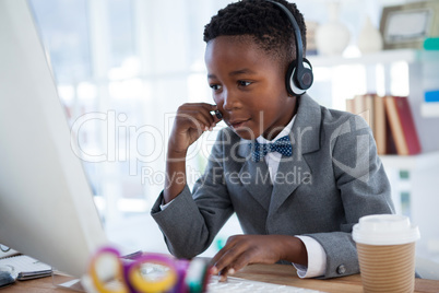Businessman wearing headphone while using computer