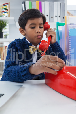 Boy pretending as businessman talking on land line phone