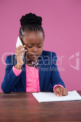 Businesswoman talking on mobile phone while reading report