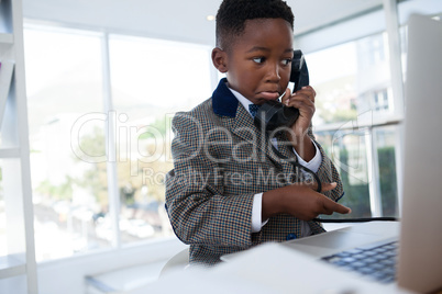 Businessman making face while talking on telephone
