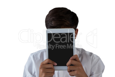 Teenage boy hiding his face behind digital tablet