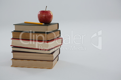 Apple and pencil on book stack