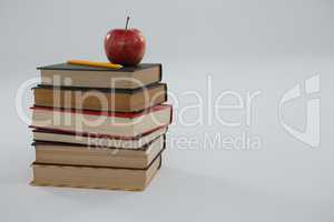 Apple and pencil on book stack