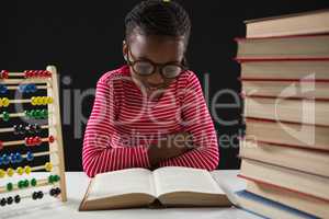 Schoolgirl reading book against black background