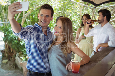 Couple taking selfie while having cocktail at counter