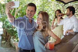 Couple taking selfie while having cocktail at counter