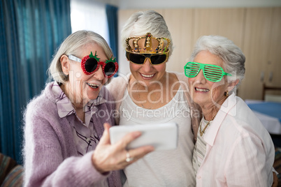 Senior women wearing novelty glasses taking selfie through smart phone