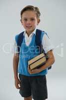 Portrait of happy schoolboy holding books against white background