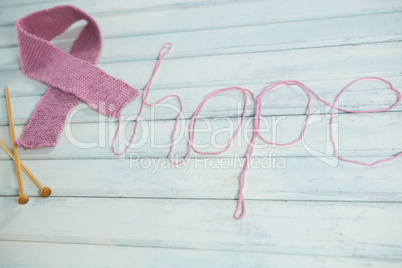 High angle view of pink Breast Cancer Awareness ribbon by hope text and crochet needles