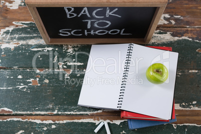 Books, apple and slate board with back to school text