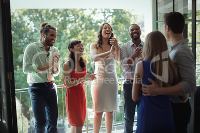 Group of friends applauding couple during party