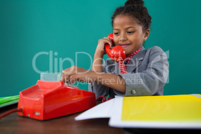 Smiling businesswoman dialing numbers on land line phone