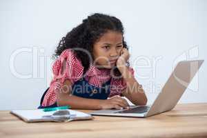 Businesswoman with hand on chin using laptop