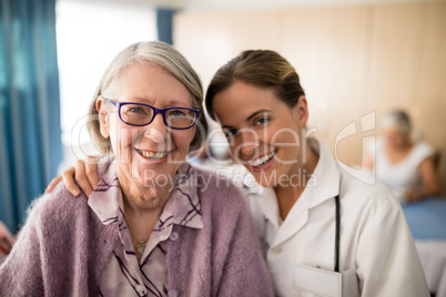 Portrait of smiling female doctor standing arm around senior woman