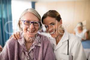 Portrait of smiling female doctor standing arm around senior woman