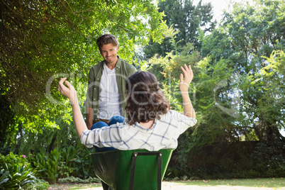 Man interacting with woman while pushing wheelbarrow in garden