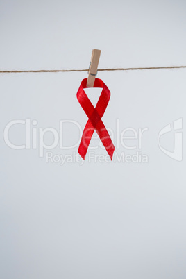 Close-up of red AIDS Awareness ribbon hanging from clothespin on string