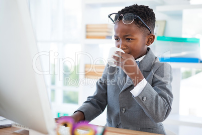 Businessman using computer while drinking coffee