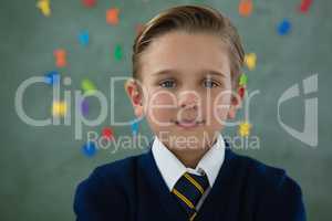 Smiling schoolboy standing against chalkboard