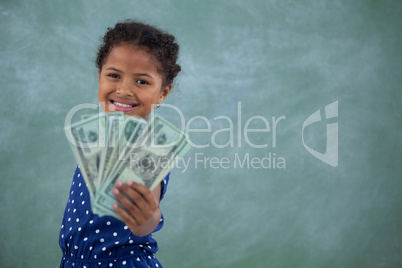 Portrait of happy girl showing paper currency