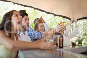 Friends watching football match at counter in restaurant