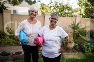 Portrait of smiling senior friends carrying exercise mats