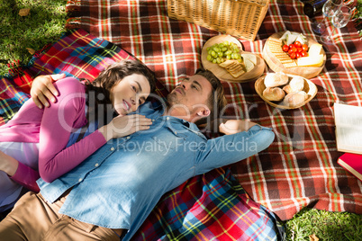 Couple lying on picnic blanket in park