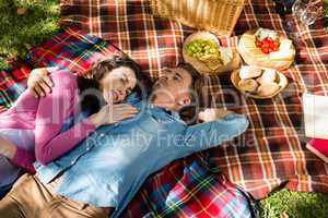 Couple lying on picnic blanket in park
