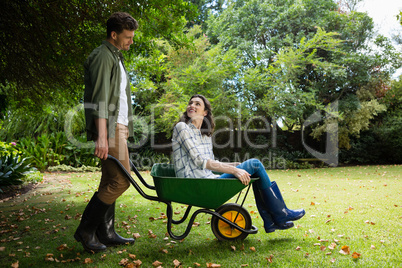 Man interacting with woman while pushing wheelbarrow in garden Man interacting with woman while pushing wheelbarrow in garden