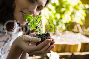 Smiling woman holding sapling plant in garden