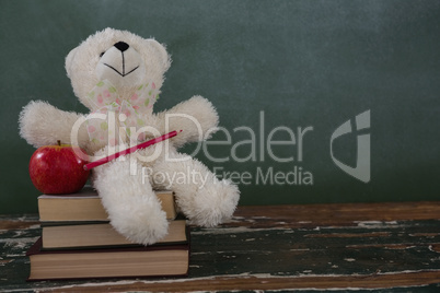 Teddy bear, pencil and apple on stack of books