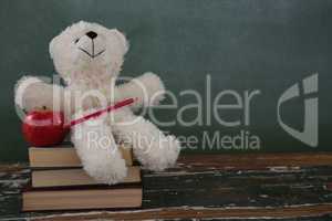 Teddy bear, pencil and apple on stack of books