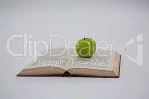 Green apple on open book