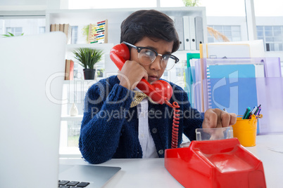 Boy pretending as businessman using land line phone